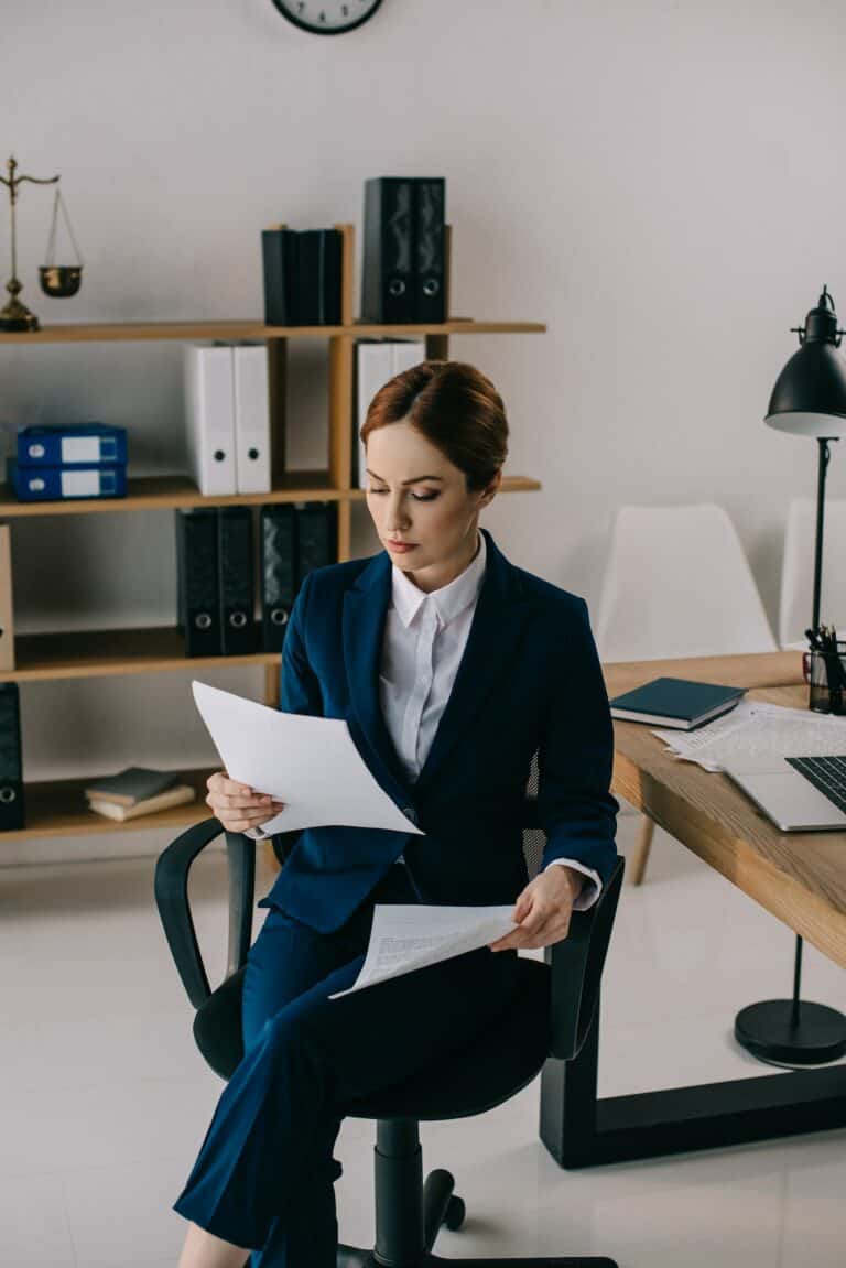 female lawyer in suit with documents in hands at workplace in office