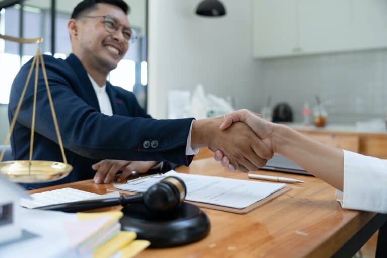 lawyer or attorneys shaking hand with client after consultation discussing a contract agreement
